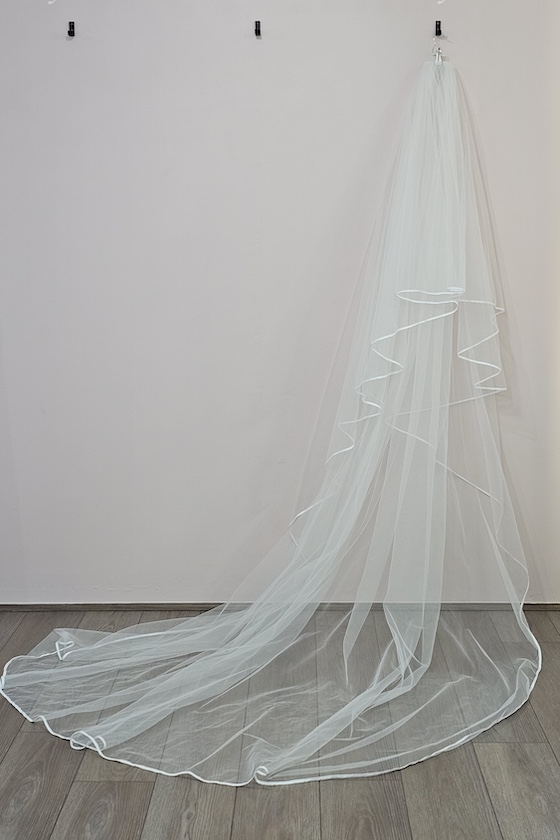 Cathedral Veil with Piped Edge. A wide-cut cathedral veil finished with a sleek piped edge, creating a dramatic yet refined frame that enhances the bridal silhouette.